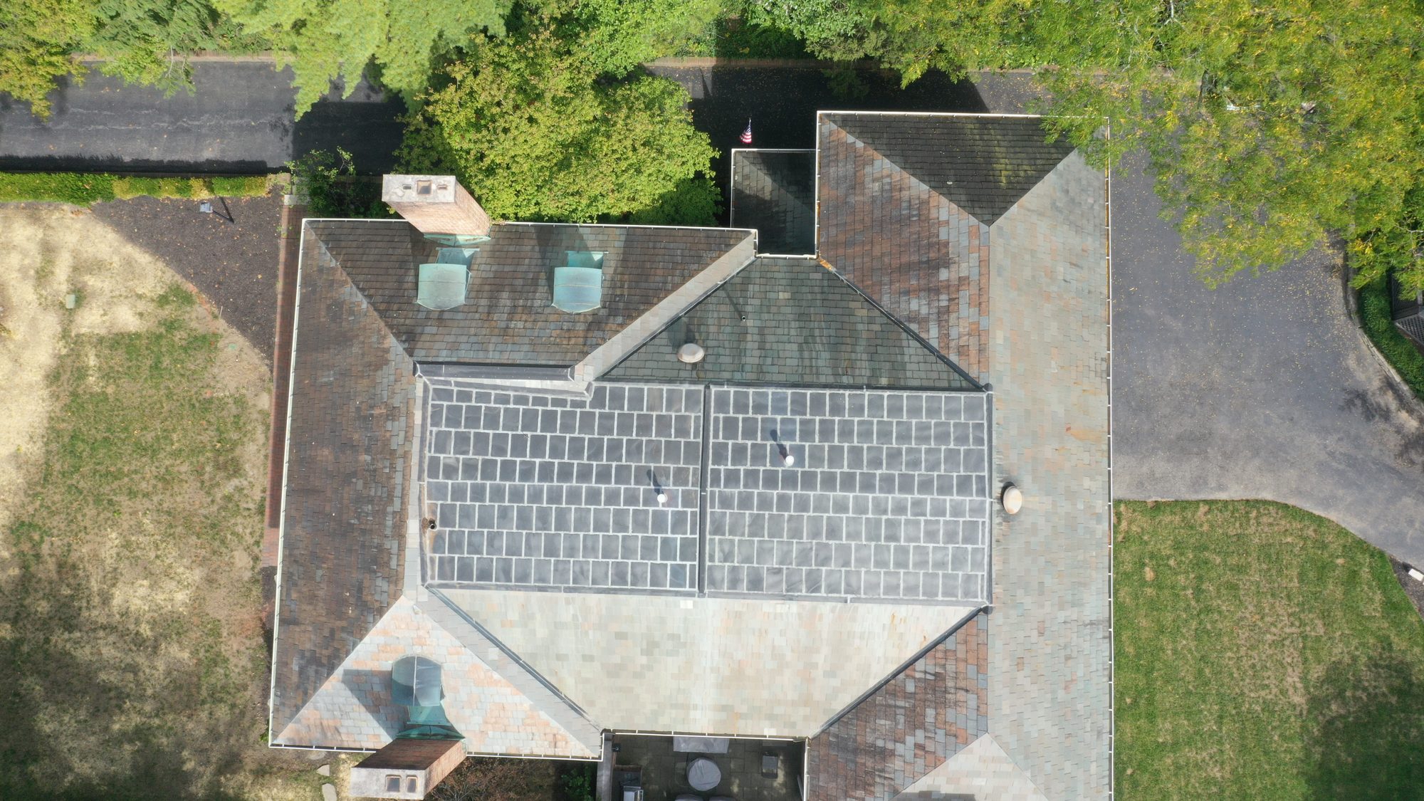Slate roof around brick chimney in Bexley showing algae growth before cleaning