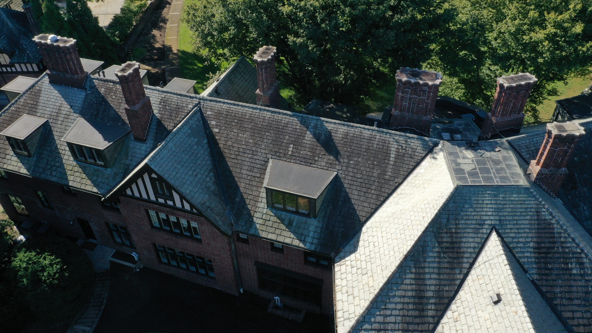 Slate roof mansion in Bexley Ohio before cleaning showing dark algae and lichen growth on Tudor-style home