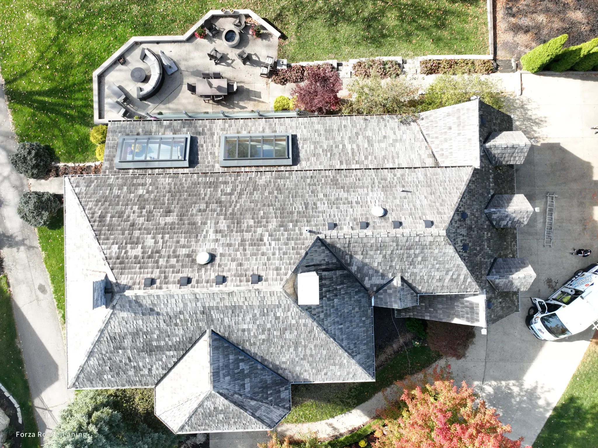 Before cedar roof cleaning - overhead drone view of entire cedar shake roof with dark algae and weathering across full surface, multiple skylights visible, complex roof geometry, Forza van in driveway, Muirfield Village Dublin Ohio