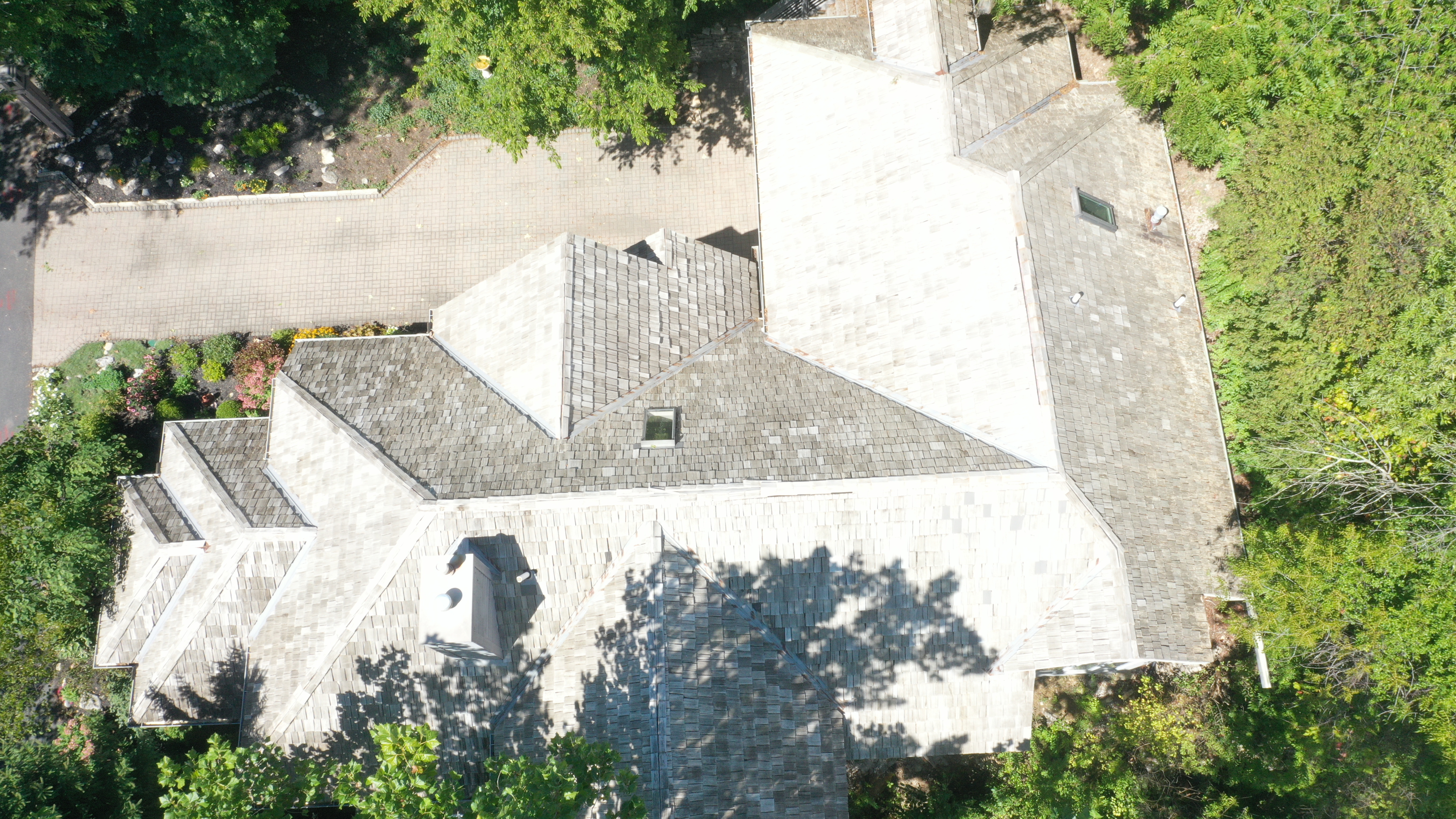 After: Detail view of complex roof geometry with golden-tan cedar shakes, multiple hips and valleys, The Quarry Dublin Ohio