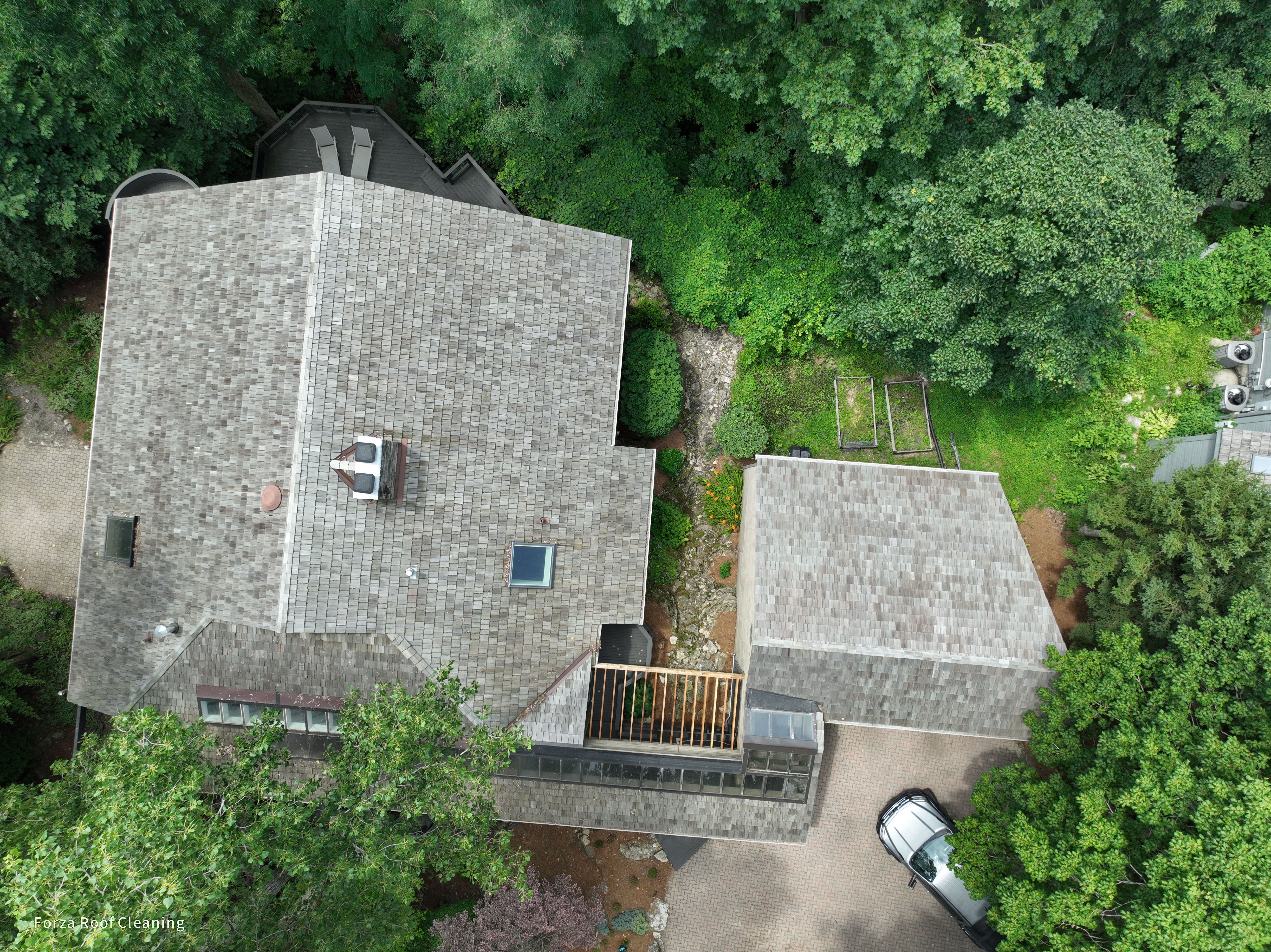 Before cedar roof cleaning - overhead view of quarry-side home with gray-black weathered cedar shakes on main house and outbuilding, stone chimney, skylight, wooden deck, The Quarry Dublin Ohio