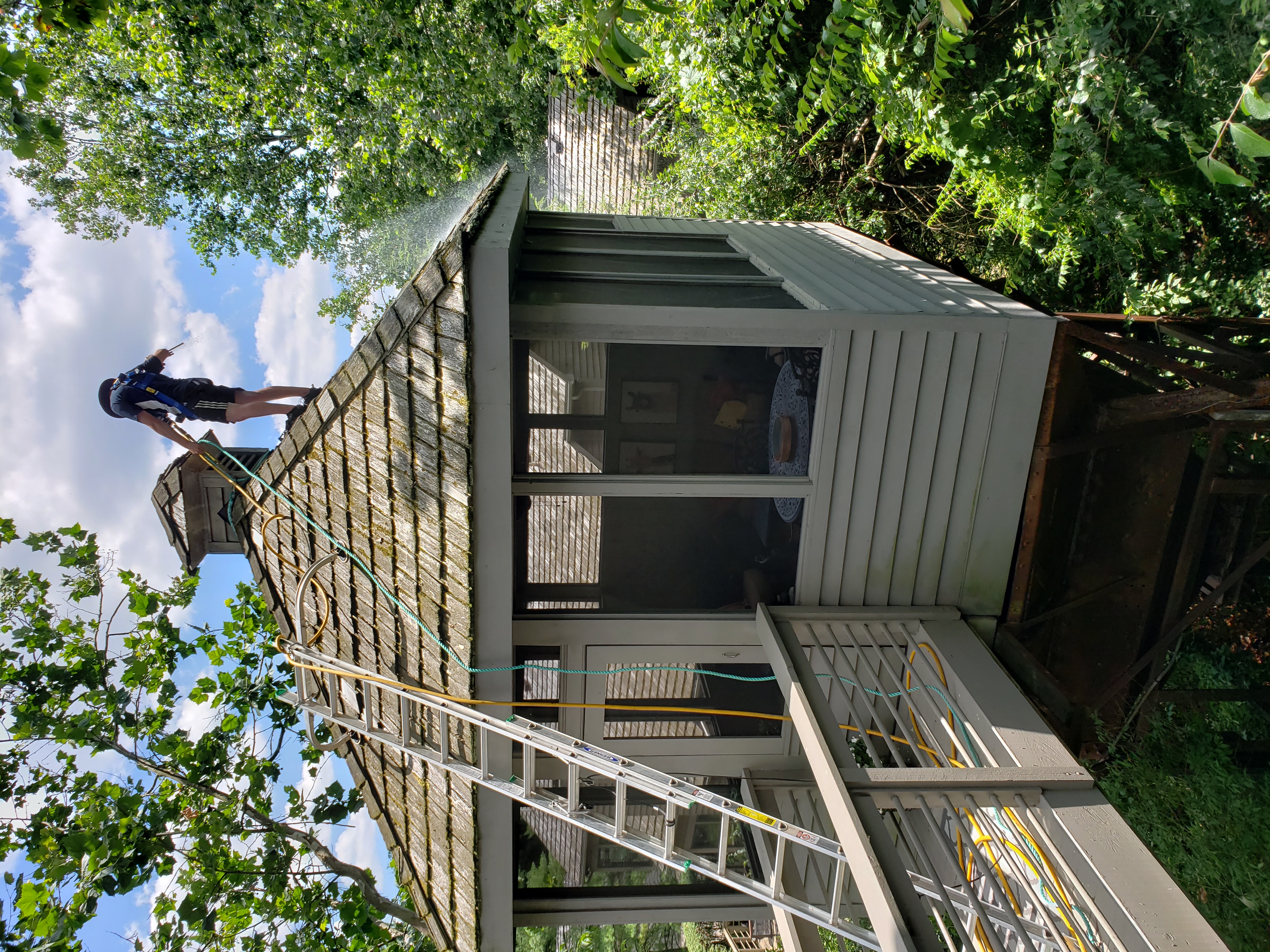 Safety harness cedar shake roof cleaning on elevated porch above ravine in The Quarry Dublin