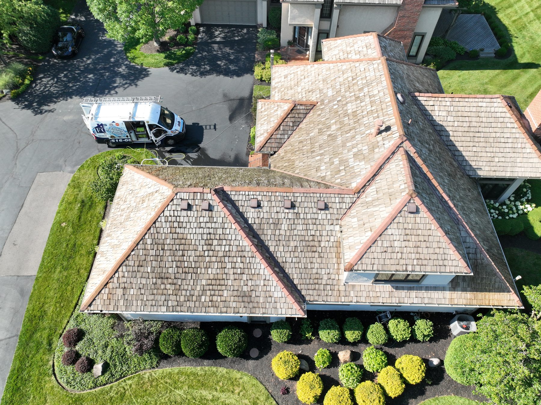After cedar roof cleaning - front-angled view showing golden honey-brown restored shakes, Forza van with logo visible in driveway, beautiful landscaping, The Sanctuary Columbus Ohio