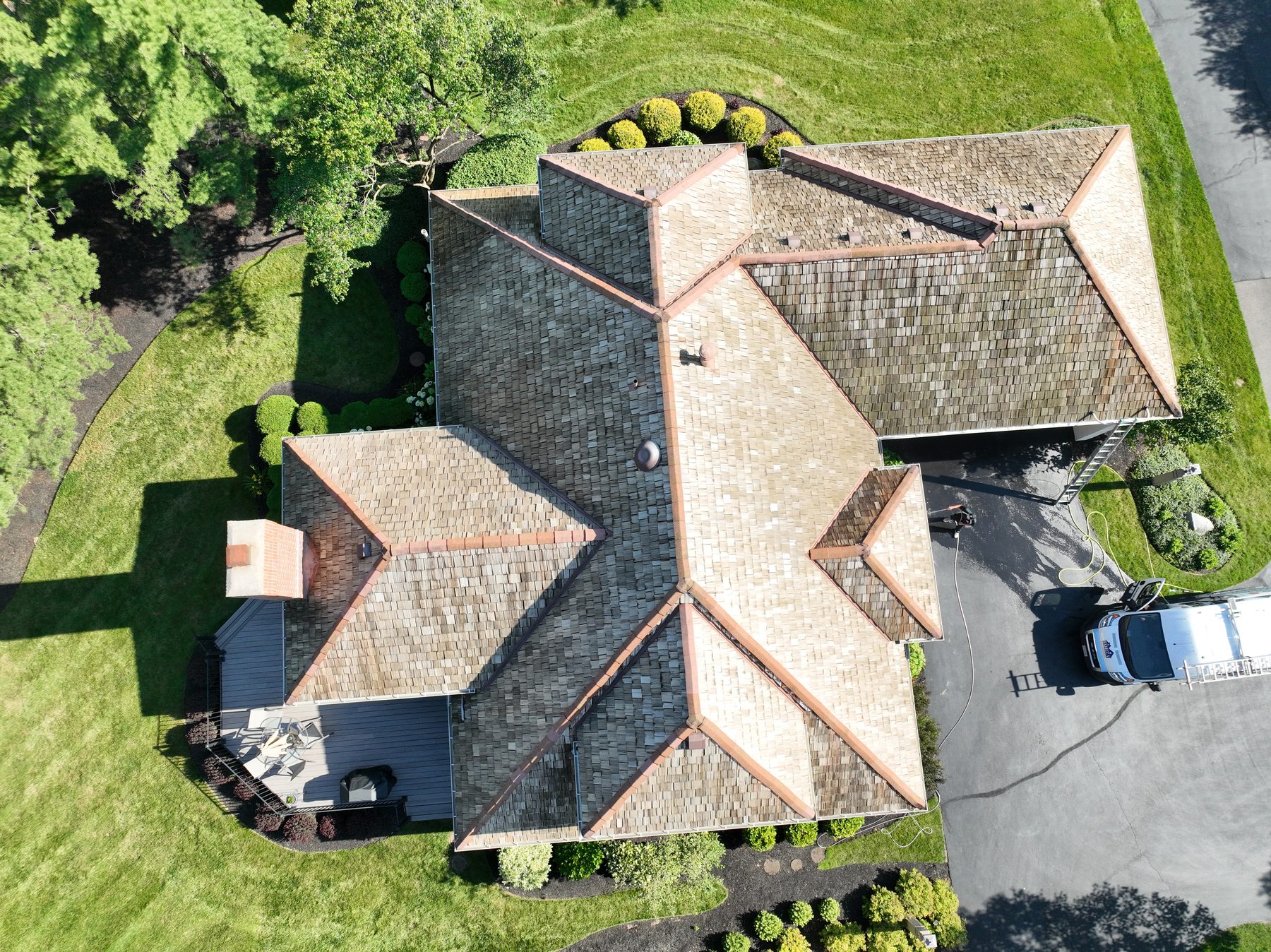 After cedar roof cleaning - full roof footprint overhead showing golden-brown restored shakes, Forza van with ladder visible, deck and patio area, The Sanctuary Columbus Ohio