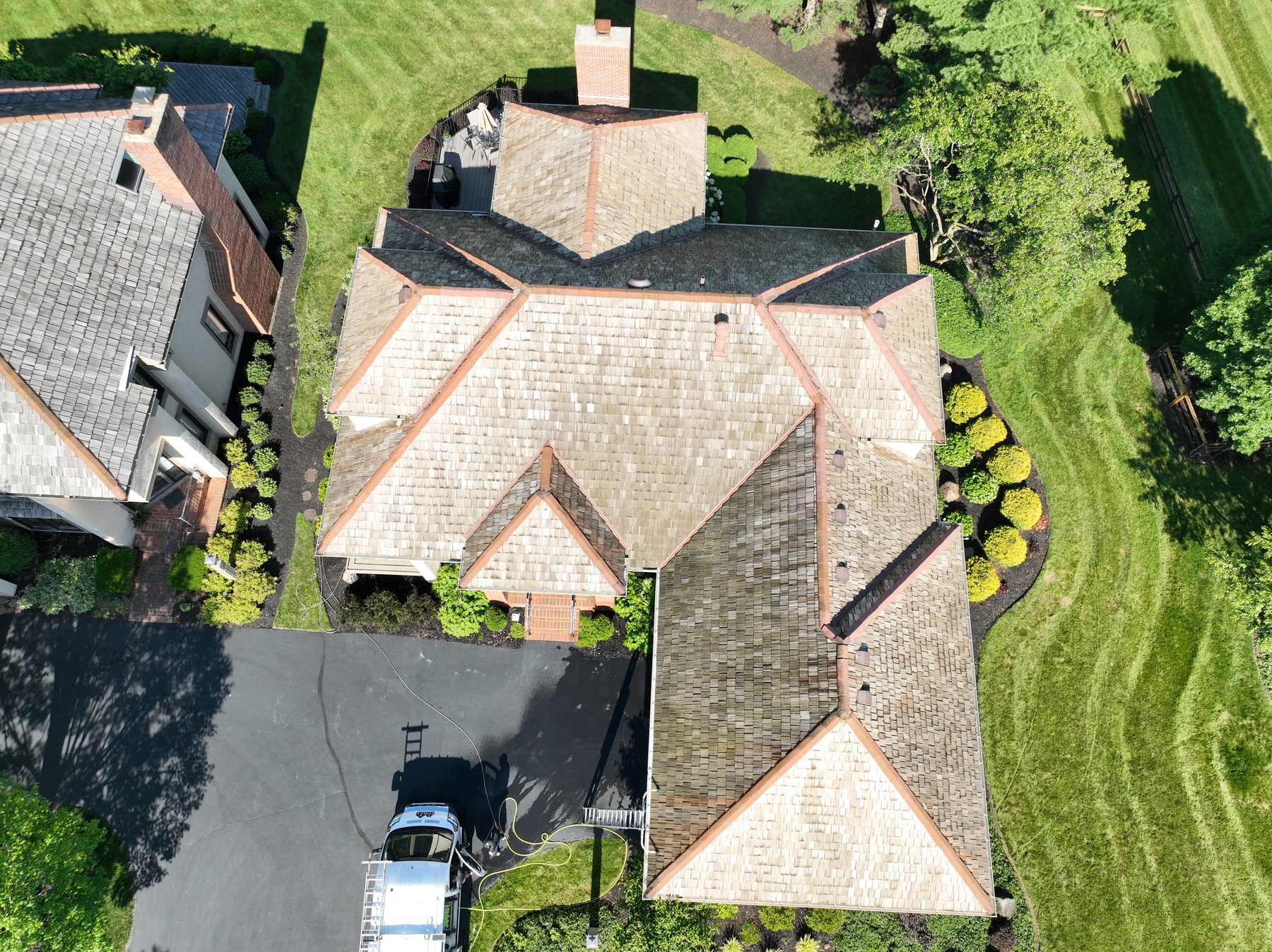 After cedar roof cleaning - overhead view showing cedar shakes restored to golden honey-brown color, Forza van in driveway, neighbor's untreated dark roof visible for contrast, The Sanctuary Columbus Ohio