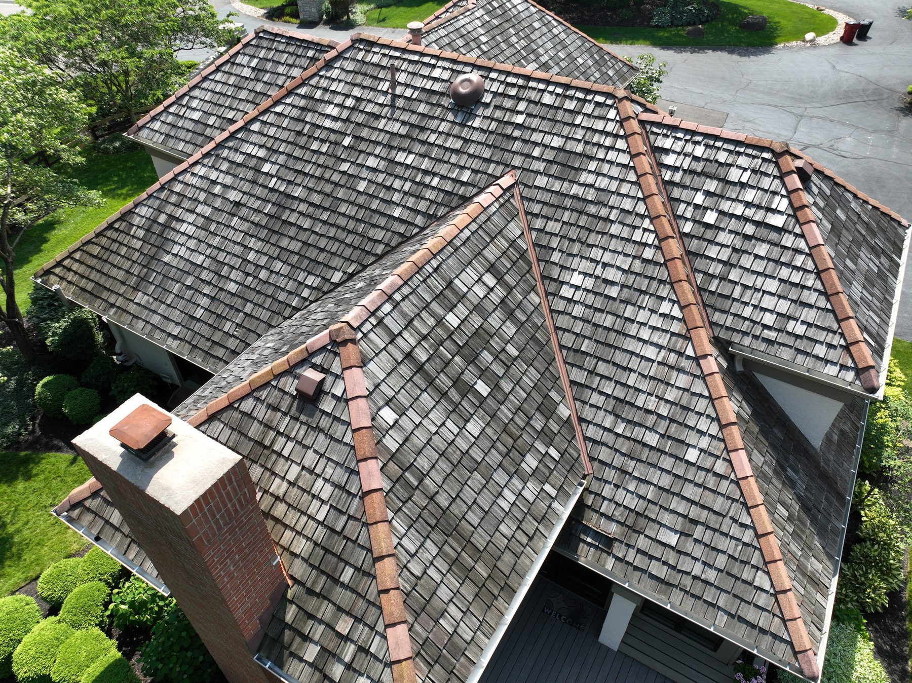 Before cedar roof cleaning - chimney side angle showing brick chimney with dark weathered cedar shakes and copper ridge caps, The Sanctuary Columbus Ohio