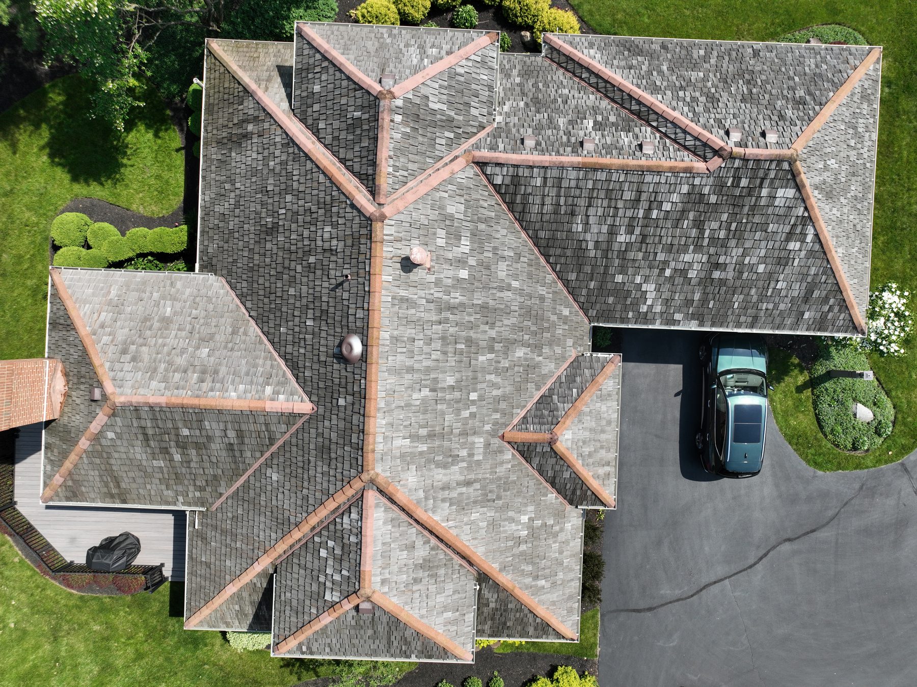 Before cedar roof cleaning - full roof footprint overhead showing dark weathered cedar shakes with copper ridge caps and lichen patches, ravine trees visible, The Sanctuary Columbus Ohio