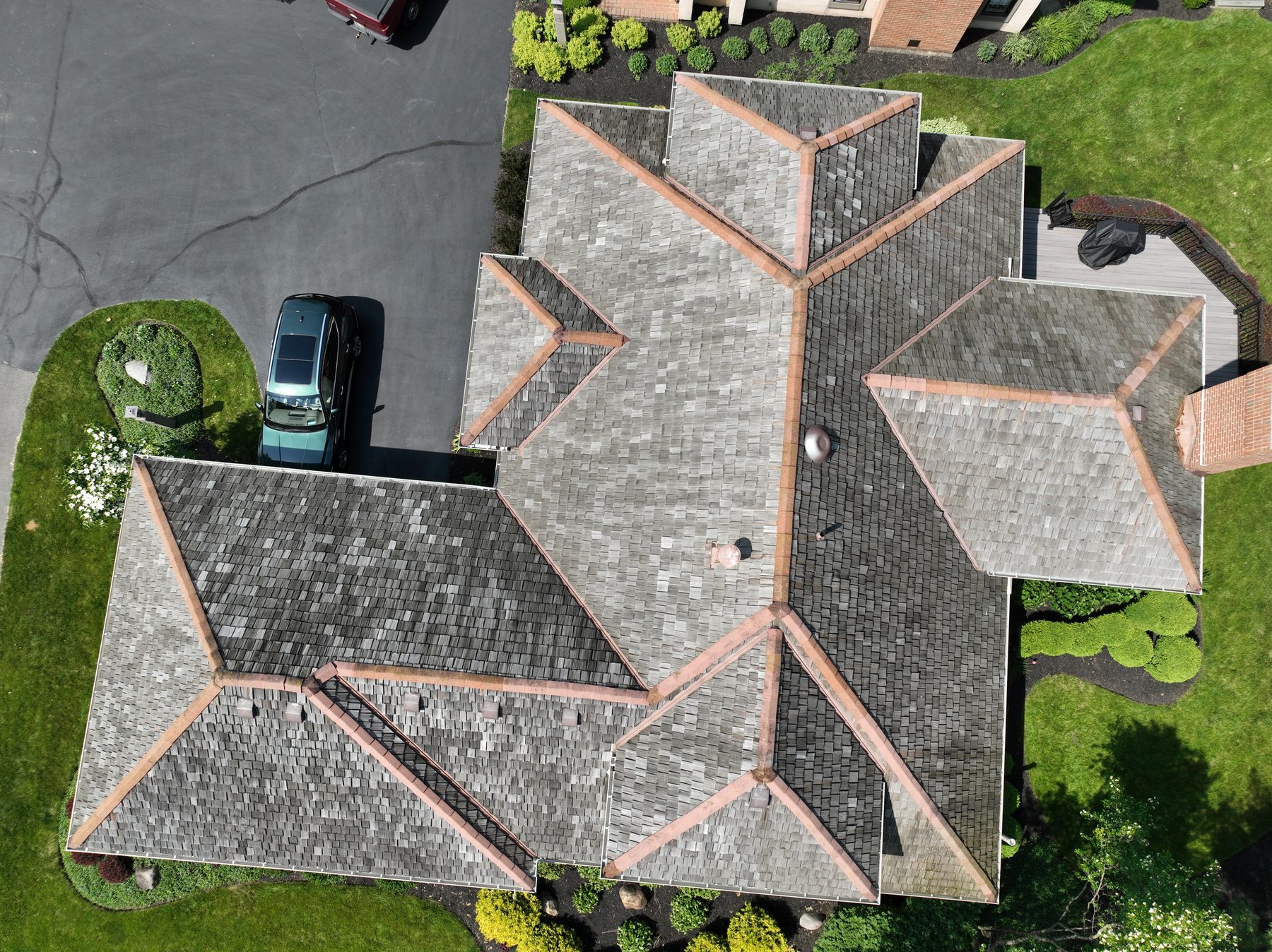 Before cedar roof cleaning - overhead view of cedar shake roof with dark gray-black weathering, white lichen spots, and copper ridge caps, The Sanctuary Columbus Ohio