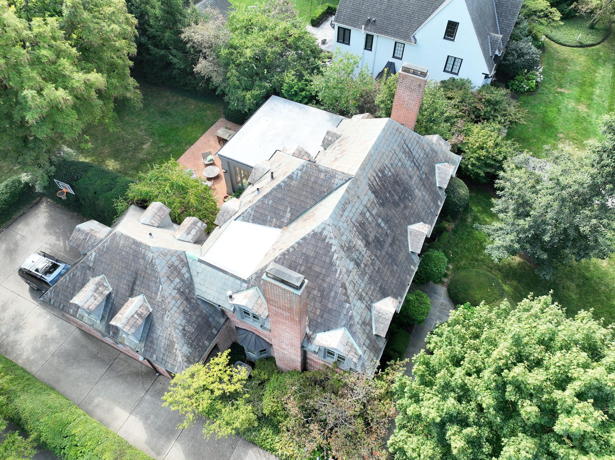 Brick Colonial slate roof in Bexley before cleaning showing dark algae on dormers and gables