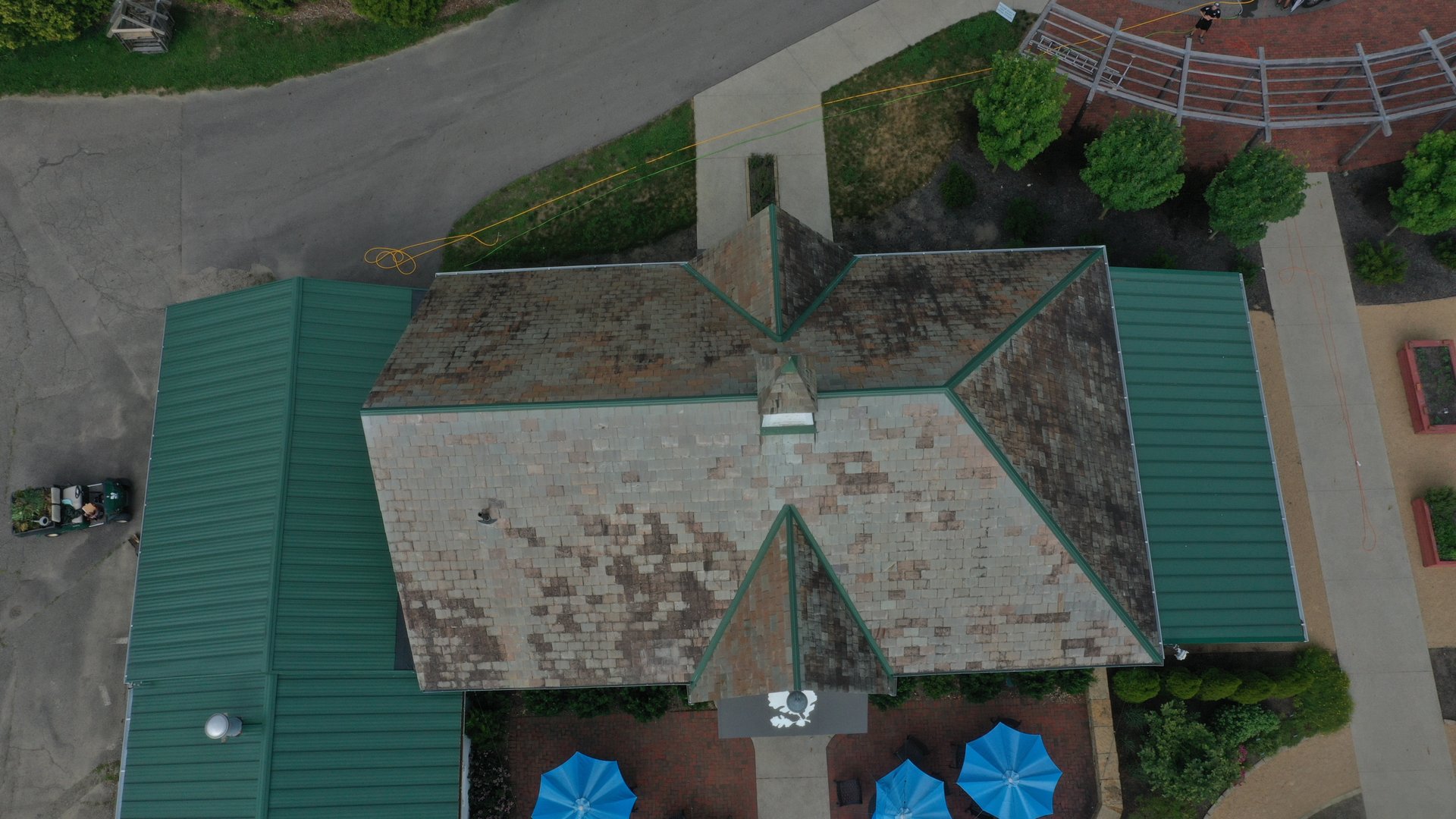 Before roof cleaning in Newark Ohio — heavy lichen and moss on commercial slate roof with green metal additions