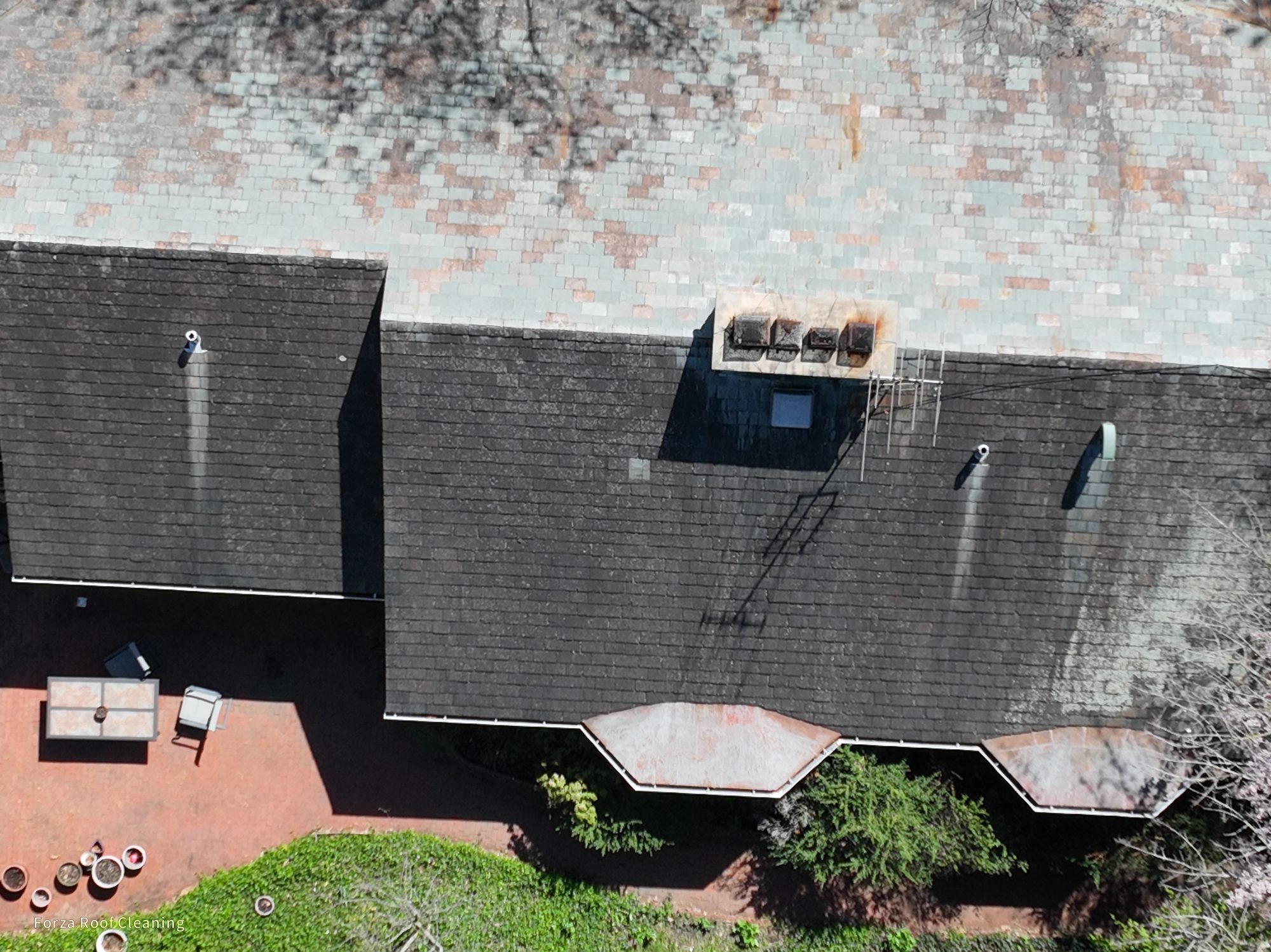 Side view of slate roof in Bexley with dark algae staining before cleaning